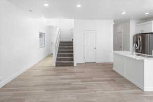 Unfurnished living room with stairway, recessed lighting, and light wood-style floors