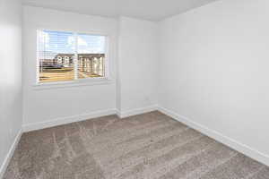 Spare room featuring carpet flooring and baseboards