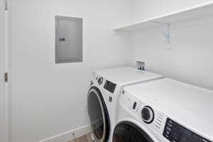 Laundry area with separate washer and dryer, electric panel, and wood finished floors