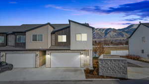 Modern home with a garage, stone siding, driveway, and a mountain view