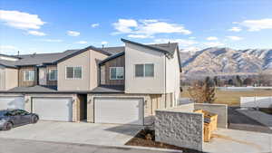 View of front of house featuring a garage, stone siding, driveway, and a mountain view