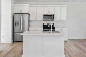 Kitchen featuring appliances with stainless steel finishes, white cabinets, and light countertops