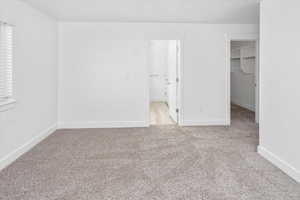 Unfurnished bedroom with a spacious closet and light carpet