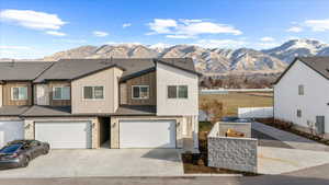 View of front facade featuring stone siding, a garage, a mountain view, and driveway