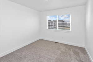 Spare room with baseboards and light colored carpet