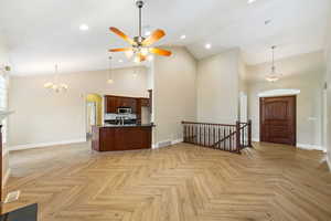 Entrance foyer with arched walkways, a chandelier, ceiling fan, high vaulted ceiling, and recessed lighting