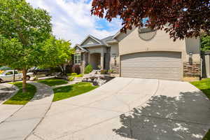View of front of house featuring stone siding, stucco siding, driveway, and an attached garage