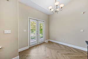 Spare room featuring baseboards and a chandelier