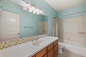 Full bathroom featuring shower / tub combo with curtain, vanity, tile patterned flooring, and decorative backsplash