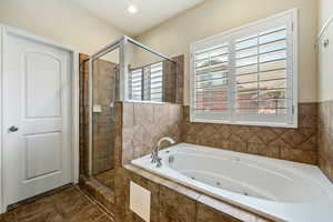 Full bath featuring a stall shower, a tub with jets, and tile patterned flooring