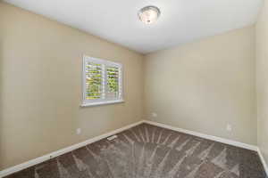 Empty room with baseboards and dark colored carpet