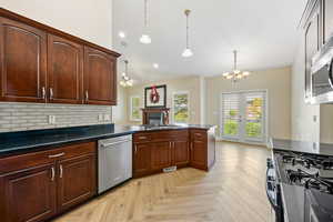 Kitchen with tasteful backsplash, appliances with stainless steel finishes, dark countertops, a ceiling fan, and plenty of natural light