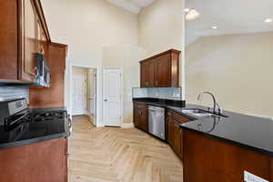 Kitchen with dark countertops, backsplash, stainless steel appliances, high vaulted ceiling, and a peninsula