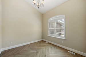 Unfurnished room featuring lofted ceiling and a chandelier