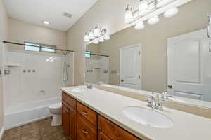 Bathroom featuring double vanity, bathing tub / shower combination, and tile patterned floors