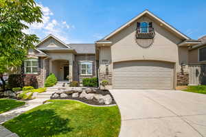View of front of house featuring stone siding, driveway, a garage, a front yard, and stucco siding