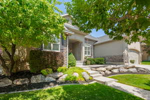 View of front of home with a garage, stone siding, a front lawn, stucco siding, and concrete driveway