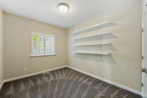 Unfurnished room featuring dark carpet and baseboards