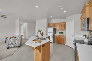 Kitchen with appliances with stainless steel finishes, a center island with sink, light countertops, recessed lighting, and light tile patterned flooring