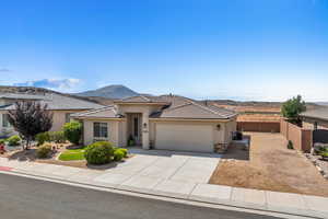 View of front of property featuring a mountain view, a garage, driveway, and stucco siding