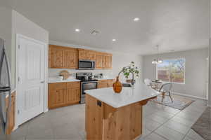 Kitchen with stainless steel appliances, light countertops, light tile patterned floors, a kitchen island with sink, and recessed lighting