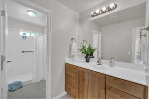 Bathroom with vanity, curtained shower, and tile patterned flooring