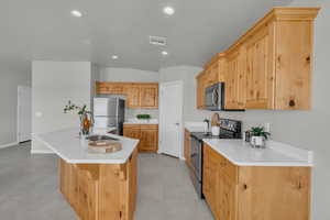 Kitchen featuring appliances with stainless steel finishes, a center island with sink, recessed lighting, light countertops, and light tile patterned floors