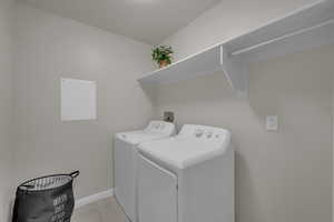 Laundry area featuring independent washer and dryer and light tile patterned floors