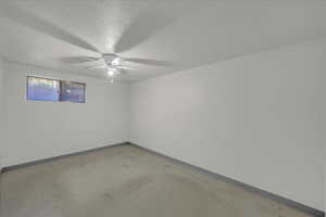 Empty room featuring a textured ceiling, a ceiling fan, and light flooring