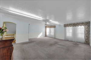 Spare room with ceiling fan, carpet floors, and a textured ceiling