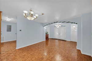 Spare room featuring a chandelier, arched walkways, and electric panel