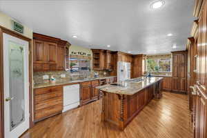 Kitchen featuring healthy amount of natural light, brown cabinets, a textured ceiling, light wood-style floors, and recessed lighting