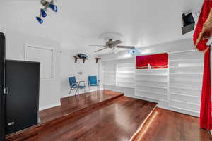Unfurnished living room featuring dark wood-style floors and a ceiling fan