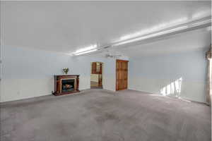 Unfurnished living room with carpet floors, ceiling fan, a textured ceiling, and ornamental molding