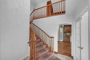 Stairway with arched walkways and tile patterned flooring
