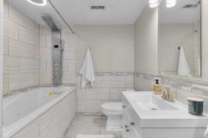 Full bath with tile walls, vanity, tile patterned flooring, a combined bath / shower with jetted tub.