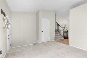 Spare room featuring light carpet and stairs