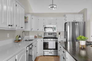 Kitchen featuring appliances with stainless steel finishes, white cabinetry, light wood-style floors, and open shelves