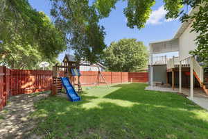 Fenced backyard with a playground, a wooden deck, stairway, and a patio area