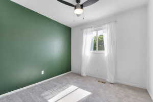 Carpeted spare room featuring ceiling fan and baseboards