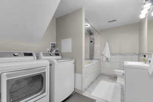 Washroom featuring washer and clothes dryer, tile, and light tile patterned flooring