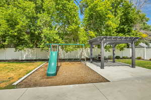 View of jungle gym featuring a fenced backyard, a pergola, and a patio area