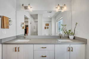 Full bathroom featuring double vanity, a stall shower, and a spacious closet