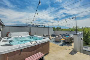 View of patio with a hot tub, a mountain view, and an outdoor living space with a fire pit