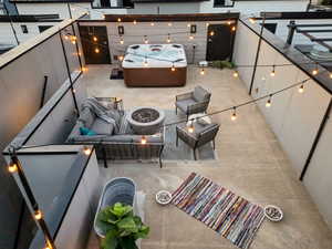 View of patio / terrace with a hot tub and an outdoor living space with a fire pit