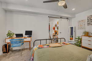 Bedroom with a barn door, an office area, recessed lighting, carpet, and a textured ceiling