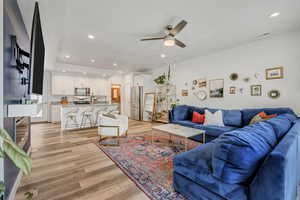 Living room with recessed lighting, light wood-type flooring, and a ceiling fan