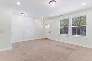 Foyer entrance with light carpet and recessed lighting
