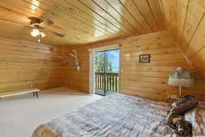 Unfurnished bedroom featuring access to exterior, wooden ceiling, wooden walls, and carpet flooring