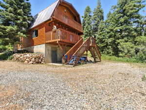 Rear view of house with a gambrel roof, stairway, a metal roof, and a wooden deck